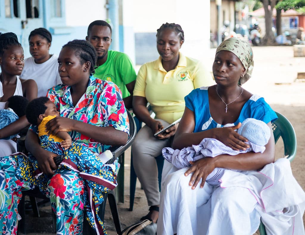 Sarah and woman with delivered baby in hand